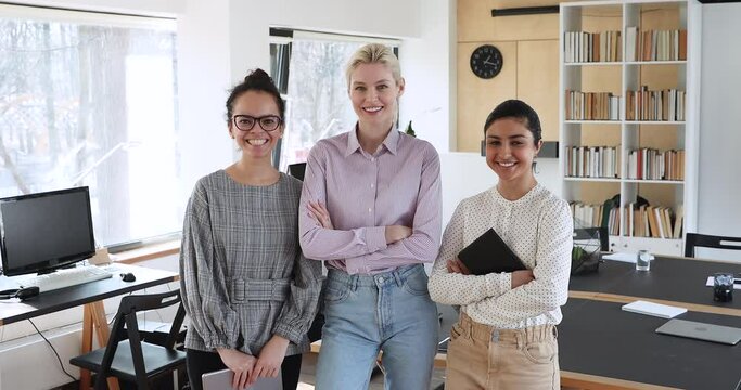 Indian mixed race african caucasian beautiful different ethnicity businesswomen colleagues posing threesome for corporate album in modern coworking area. Friendly united working team portrait concept