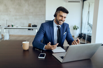 Happy entrepreneur communicating with someone via video call from his office.