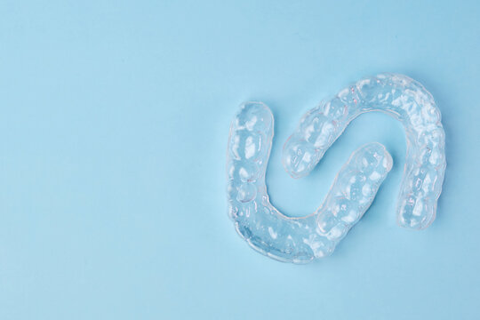 Removable teeth aligners on the blue background with copy space. Orthodontic treatment for beautiful smile.