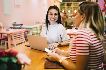 Portrait of cheerful hipster girl in optical eyewear for vision correction laughing at camera during collaborative meeting with freelance colleague, happy female students e learning togetherness