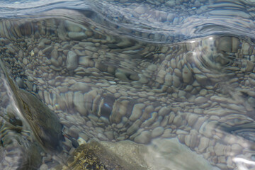 Sea stones in the sea water. Pebbles under water. The view from the top. Nautical background. Clean sea water. Transparent sea.