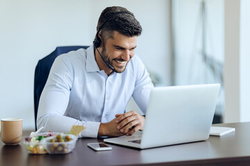 Happy entrepreneur having video call over laptop while working in the office.