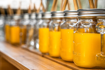 Orange juice in mason jars lined up on a wooden table outside