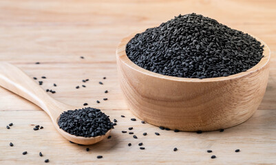 Black sesame seeds in wooden spoon and wooden bowl on table,organic food concept.