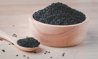 Black sesame seeds in wooden spoon and wooden bowl on table,organic food concept.