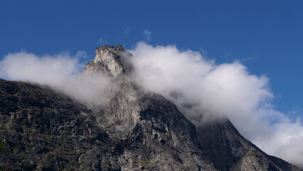 Fototapeta premium The top of a mountain surrounded by clouds near trollstigen