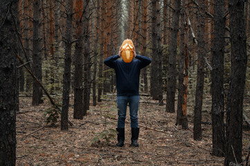 Halloween holiday. Anonymous Man holds in front of his face a glowing Halloween pumpkin in a dark forest. Faceless. Horror and fear concept.