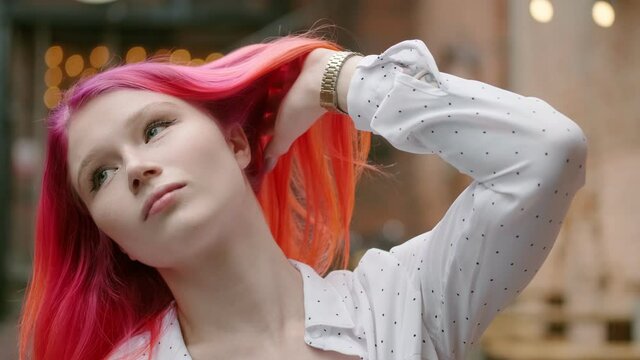 Close-up portrait of a girl with an unusual appearance and bright red hair. Young hipster woman mysteriously looks into the camera