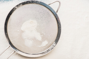 top view of white flour and metal sieve