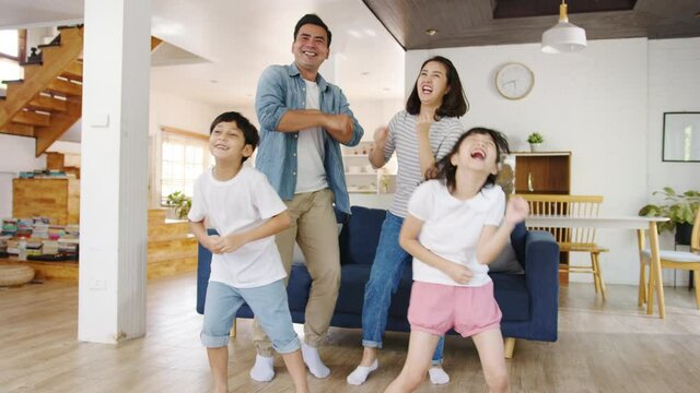 Slow motion - Happy cheerful Asian family having fun listen to music and dancing in living room at modern home. Spending time together, Social distancing, Quarantine for corona virus prevention.