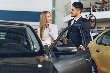 Fototapeta na wymiar Man car dealer showing a woman buyer a new car