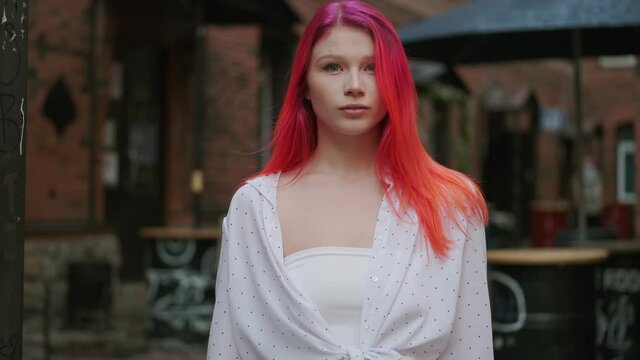 Portrait of a hipster girl with a very unusual appearance and bright red hair. Young woman mysteriously looks into the camera
