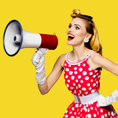 Blond woman holding megaphone, shout something. Girl in pin-up style dress in polka dot, isolated over yellow color background. Caucasian model posing in retro fashion vintage studio concept. Square.