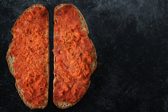 Two slices of mallorcan bread with meat spread &ldquo;Sobrasada&rdquo; typical of Majorca.  Close-up top view on dark background with empty space.