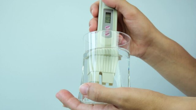 girl measures the level of water contamination in the glass with a device. Damage of Human, Eco Conservancy. Closeup.