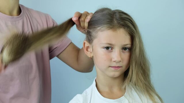 Young gerl getting her hair dressed . mother combing hair comb girl blonde. 4K.