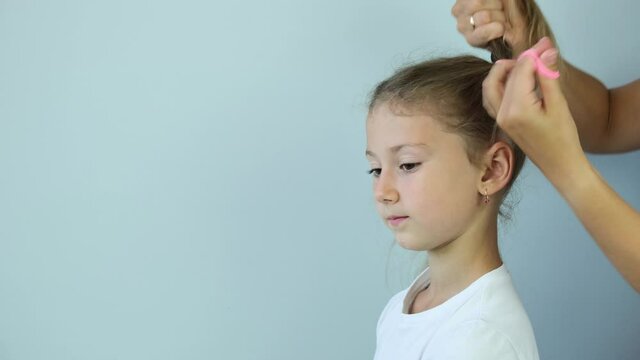 Young gerl getting her hair dressed . mother combing hair comb girl blonde. 4K.