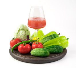A glass of freshly squeezed vegetable juice and a large selection of fresh vegetables on a round tray on a white background. Plant background. The concept of proper nutrition.