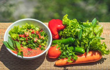 Raw vegan salad with green leaves mix vegetables in white bowl. Cooking recipe blended tomato...