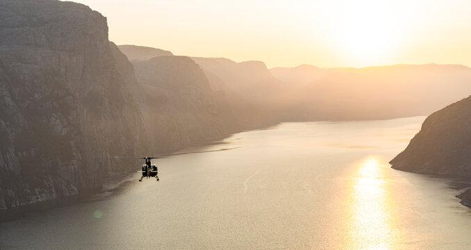 Helicopter flyinng down the amazing Lyse fjord in Norway at sunrise