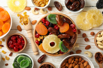 Bowls with dried fruits and nuts on white wooden background