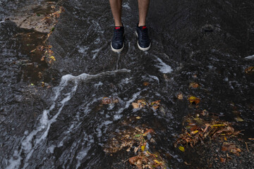 male feet are in a puddle that flows down after the rain