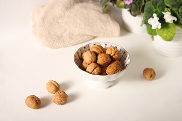 bowl with walnuts on a white background with flowers in pots. Nuts. Healthy eating. Nutritionology.