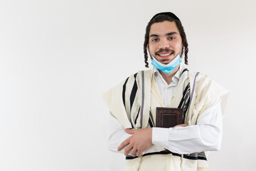 Smiling orthodox jewish man looks at camera, wearing protective mask against covid-19 pandemic.