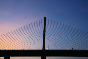 cable bridge over the river with sunset sky