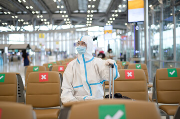 An Asian man is wearing ppe suit in International airport , Safety travel , covid-19 protection , social distancing concept