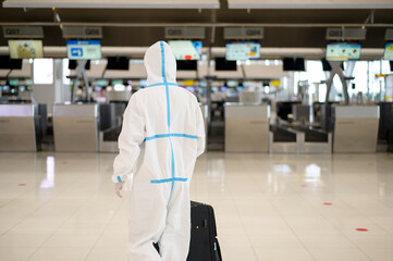 An Asian man is wearing ppe suit in International airport , Safety travel , covid-19 protection , social distancing concept