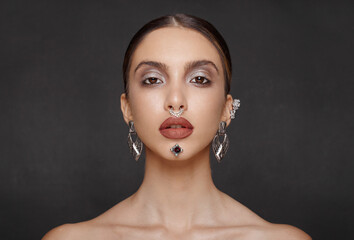 Gorgeous female model, with makeup jewelry, looking frontal at camera, posing in studio, isolated...