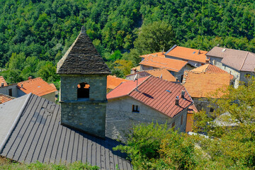 Fototapeta na wymiar Red, orange roofs. church in the village across green mountains close-up. Scenery rural view. Background. Copy space. Italy, Emilia-Romagna, Cecciolo