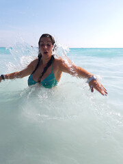 girl bathes in the waves between the waters of the white beach of Rosignano