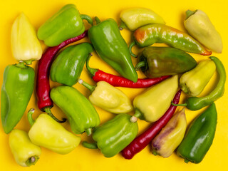 Sweet and hot pepper on a yellow background. A large number of peppers in the pile.