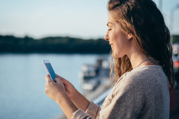 Smiling young woman looking in mobile phone
