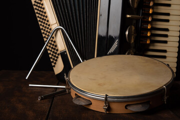 Old accordion, tambourine and triangle on rustic wooden surface with black background and Low key lighting, selective focus.