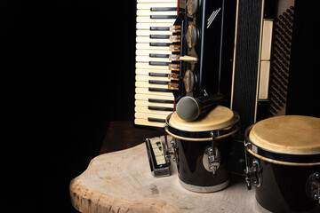 Obraz premium Old accordion, harmonica, bong and microphone on a rustic wooden surface with black background and low key lighting, selective focus.