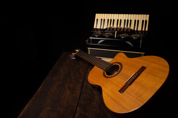 Old accordion and a beautiful guitar composing a scene on a rustic wooden surface with black...