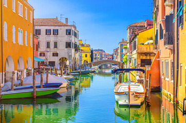 Chioggia cityscape with narrow water canal Vena with moored multicolored boats between old colorful buildings