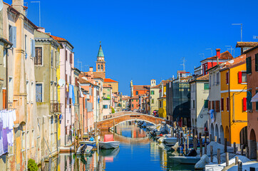Chioggia cityscape with narrow water canal Vena with moored multicolored boats between old colorful buildings