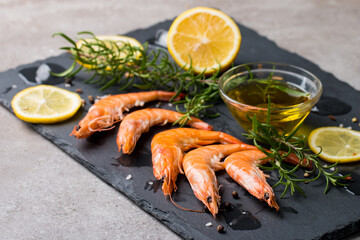 Shrimps on stone background. Grilled prawns with rosemary and lemon. 