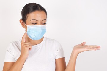 Funny Young arab woman wearing medical mask standing over isolated white background with short hair holding open palm new product. I wanna buy it!