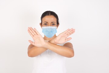 YoYoung arab woman wearing medical mask standing over isolated white background has rejection expression crossing arms and palms doing negative sign, angry face.