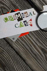 The phrase Criminal case made of letters cut from a magazine and pasted on a sheet of paper. Bank cards stick out from under the paper. There is a magnifying glass.
