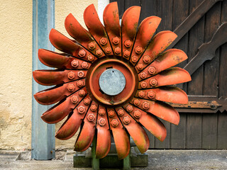 An old orange Pelton wheel hanging outside