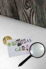 The phrase Criminal case made of letters cut from a magazine and pasted on a sheet of paper. The sheet with the inscription lies on the laptop cover. Nearby is Bitcoin and a magnifying glass.