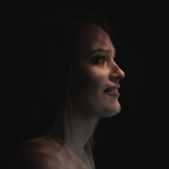 Beautiful mid adult woman with interesting pattern of light and shadow on her face. Beauty female portrait in profile.