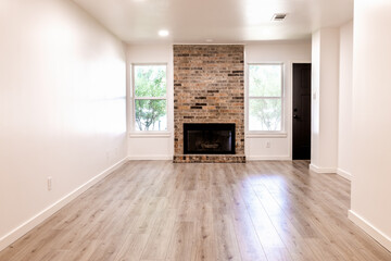 Empty living room with a fireplace, white walls and hardwood floor