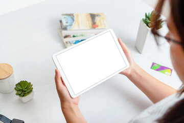 Tablet mockup in woman hands in horizontal position. Work desk in background